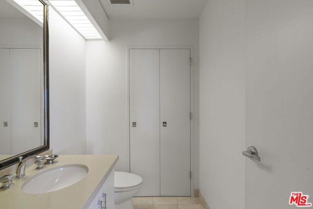 bathroom featuring vanity, tile patterned flooring, and toilet