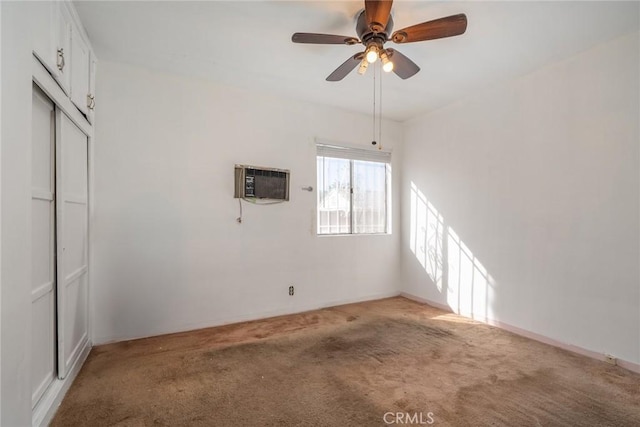 empty room with a wall mounted AC, light colored carpet, and ceiling fan