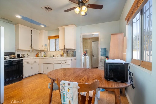 kitchen with white cabinetry, backsplash, range with gas cooktop, and light hardwood / wood-style floors