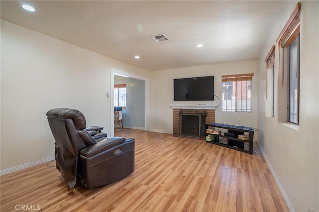 living room featuring a brick fireplace and light hardwood / wood-style flooring