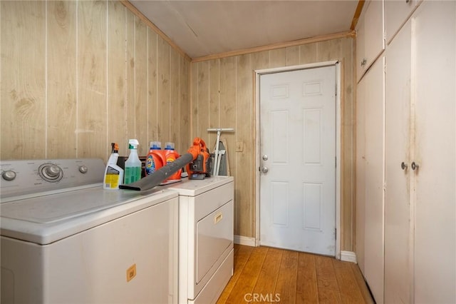 laundry room featuring washing machine and dryer, light wood-type flooring, and wood walls