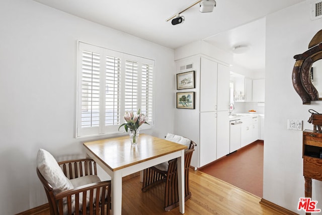 dining room featuring track lighting, sink, and light wood-type flooring