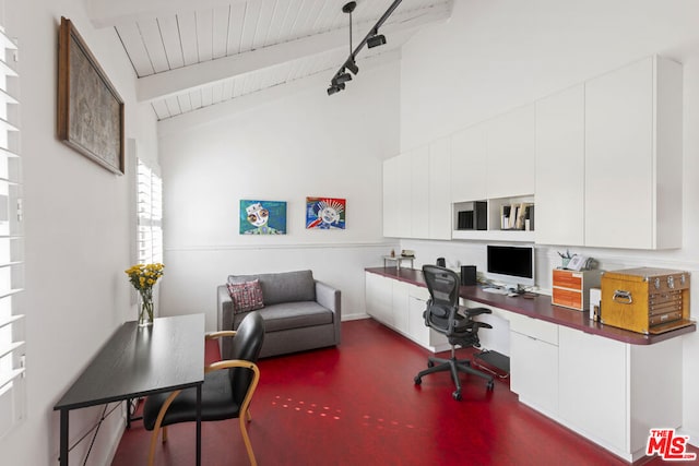 office space with track lighting, built in desk, and vaulted ceiling with beams