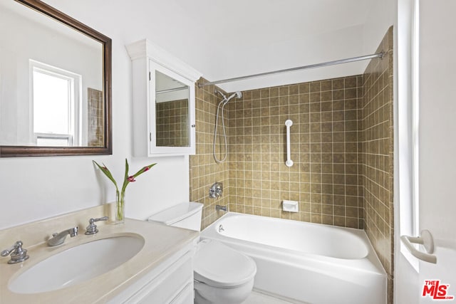 full bathroom featuring tiled shower / bath combo, vanity, and toilet