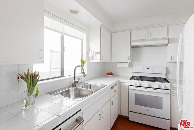 kitchen featuring sink, backsplash, white cabinets, tile counters, and white appliances