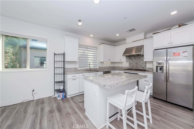 kitchen featuring light hardwood / wood-style floors, a center island, white cabinets, and appliances with stainless steel finishes