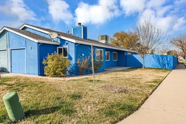 rear view of house with central AC, a yard, and a garage