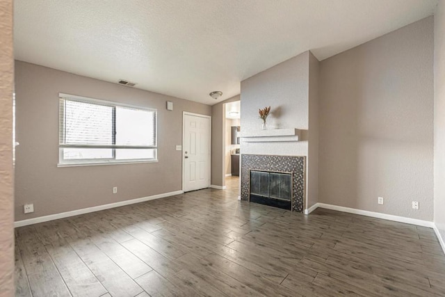 unfurnished living room featuring dark wood-type flooring, a fireplace, vaulted ceiling, and a textured ceiling