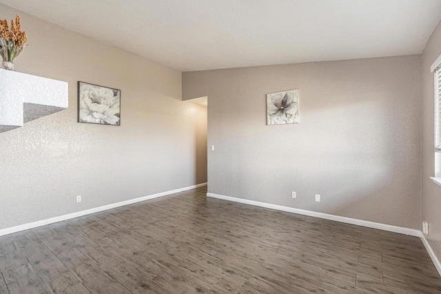 spare room featuring vaulted ceiling and dark hardwood / wood-style floors