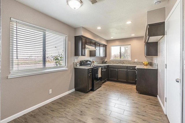 kitchen with light stone counters, black range with electric cooktop, light hardwood / wood-style flooring, and dark brown cabinetry