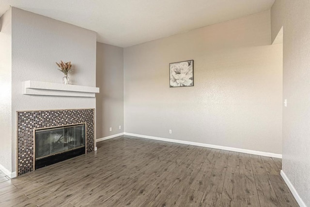 unfurnished living room featuring a tiled fireplace and dark hardwood / wood-style floors