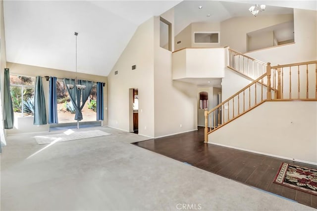 interior space featuring dark colored carpet, high vaulted ceiling, and an inviting chandelier