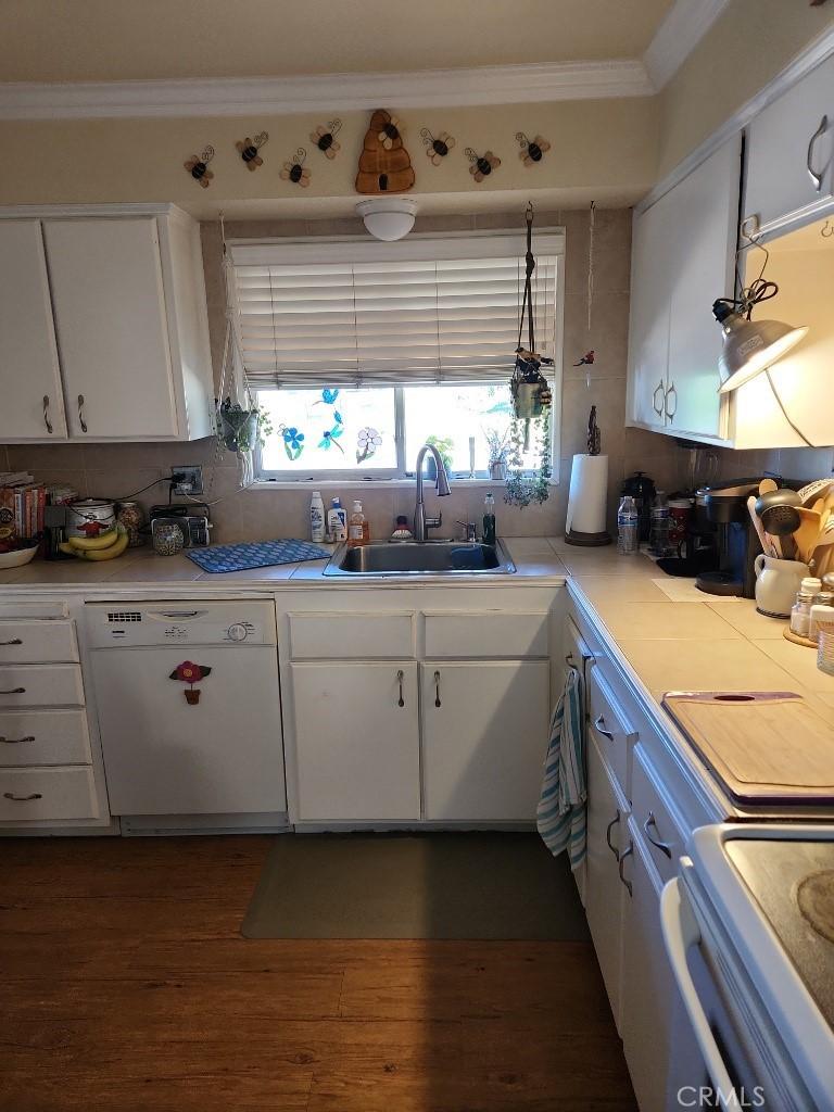 kitchen with sink, range, ornamental molding, dishwasher, and white cabinets