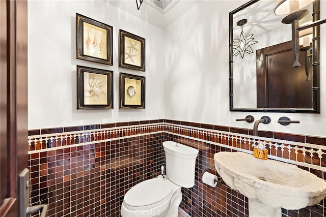 bathroom featuring tile walls and toilet