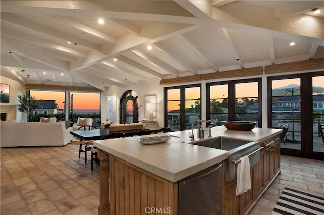 kitchen with french doors, sink, lofted ceiling with beams, a center island with sink, and dishwasher