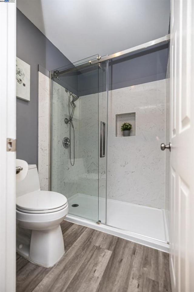 bathroom with walk in shower, hardwood / wood-style floors, and toilet