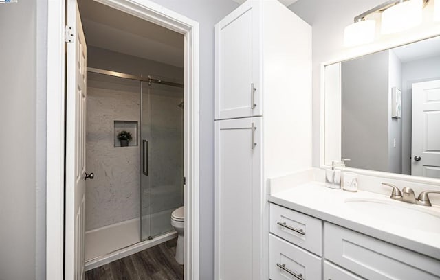 bathroom featuring an enclosed shower, vanity, hardwood / wood-style flooring, and toilet