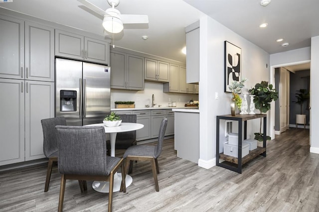 kitchen with sink, gray cabinetry, stainless steel fridge with ice dispenser, ceiling fan, and light hardwood / wood-style floors