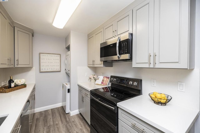 kitchen with gray cabinets, appliances with stainless steel finishes, and light hardwood / wood-style flooring