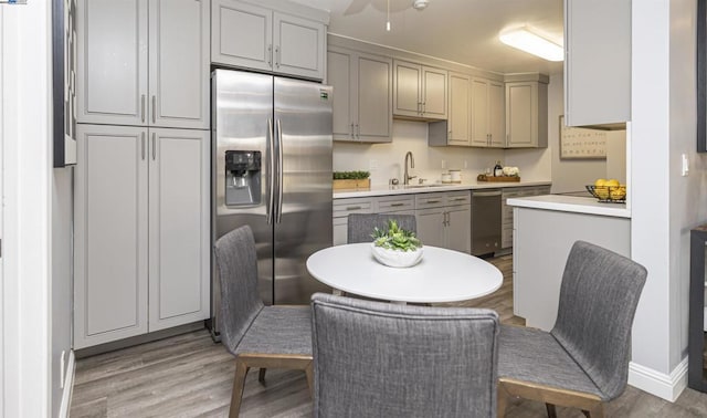 kitchen featuring stainless steel appliances, hardwood / wood-style flooring, sink, and gray cabinetry