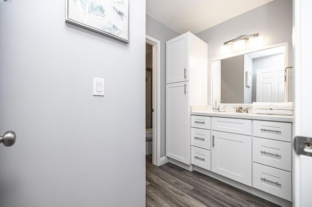 bathroom with hardwood / wood-style flooring, vanity, and toilet