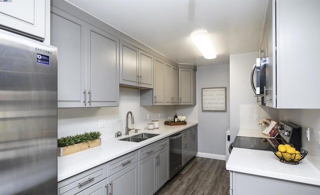 kitchen featuring appliances with stainless steel finishes, dark hardwood / wood-style flooring, sink, and gray cabinetry