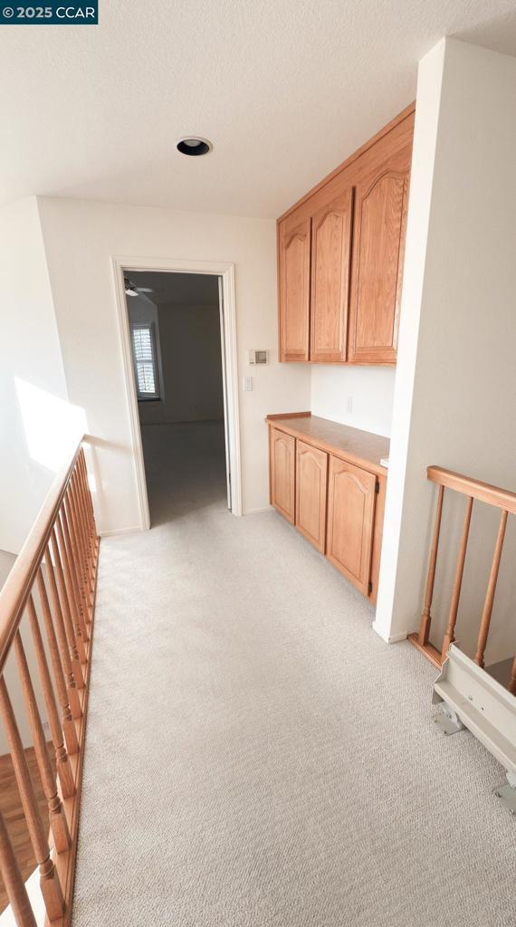 interior space featuring light colored carpet, light brown cabinetry, and a textured ceiling