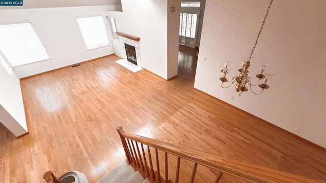 unfurnished living room with a tile fireplace, light hardwood / wood-style flooring, and a notable chandelier