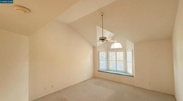 spare room featuring ceiling fan, light colored carpet, and vaulted ceiling