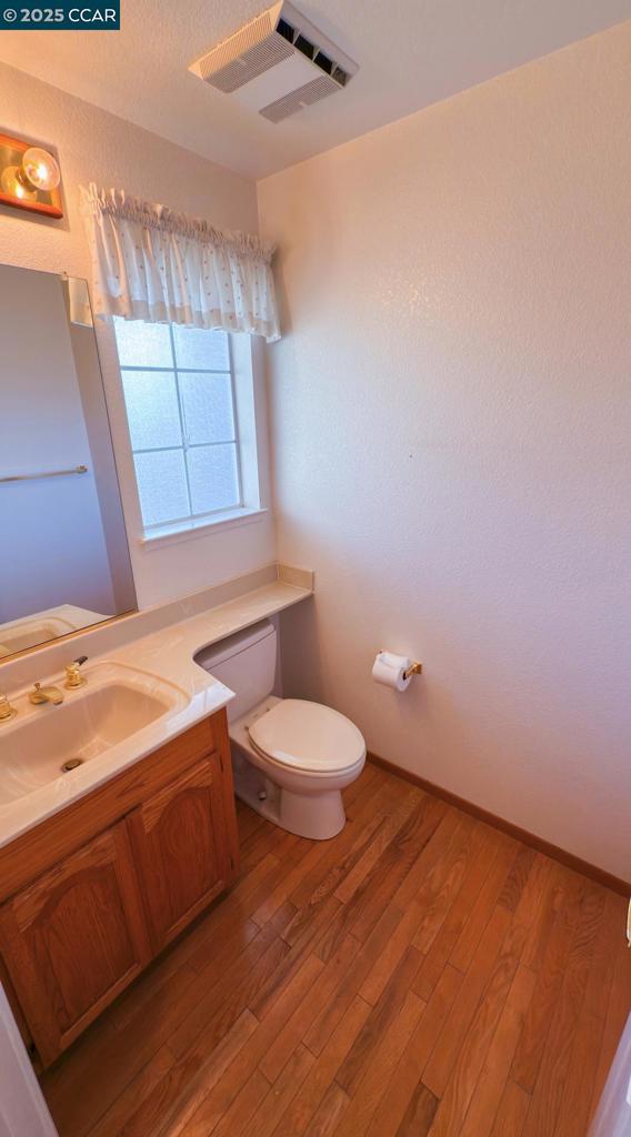 bathroom featuring wood-type flooring, toilet, and vanity