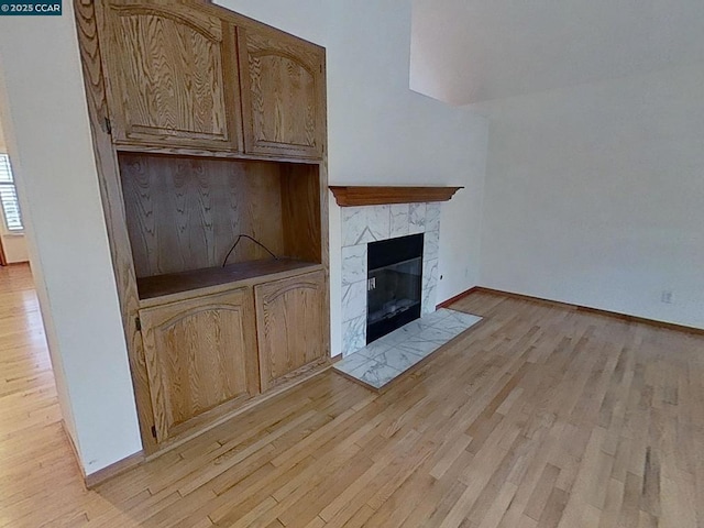 unfurnished living room featuring a tiled fireplace and light hardwood / wood-style flooring