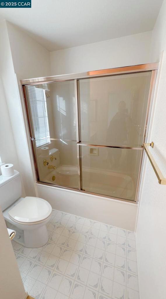 bathroom with enclosed tub / shower combo and toilet