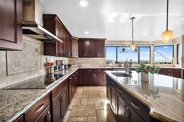 kitchen featuring decorative backsplash, hanging light fixtures, light stone countertops, wall chimney range hood, and black electric cooktop