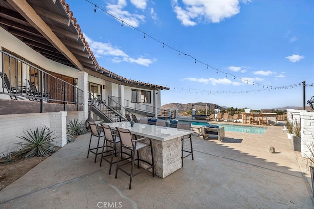 view of patio featuring a bar, a fenced in pool, and a mountain view