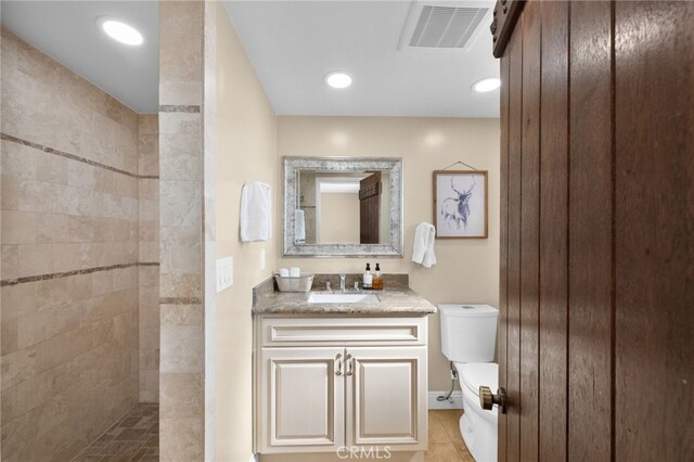 bathroom with vanity, tile patterned floors, toilet, and a tile shower