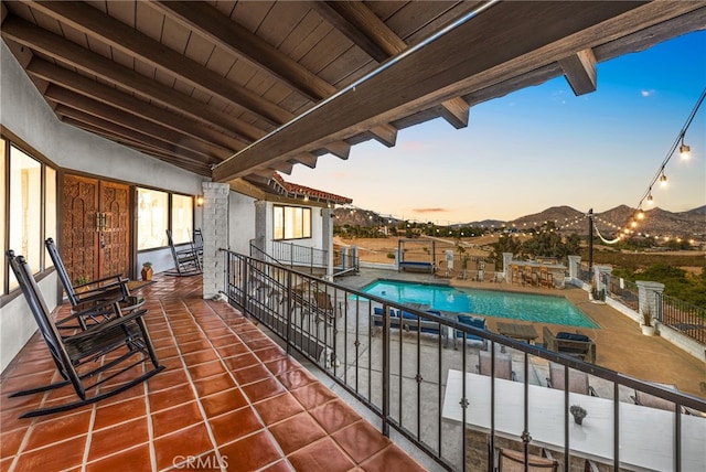 balcony at dusk featuring a mountain view and a patio