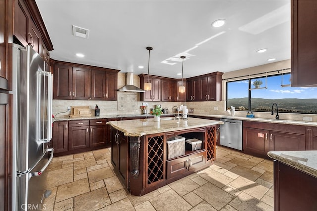 kitchen featuring stainless steel appliances, a kitchen island, a mountain view, decorative light fixtures, and wall chimney exhaust hood