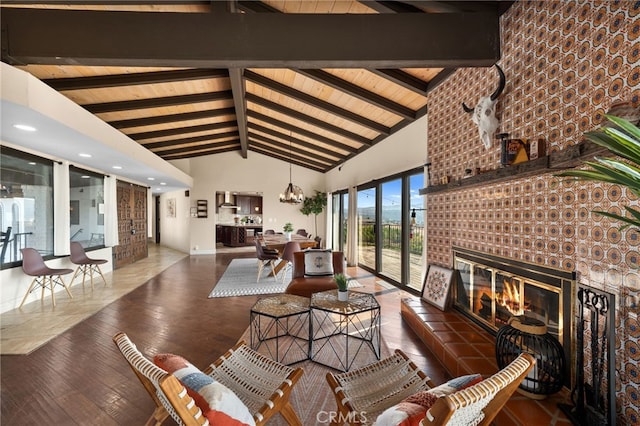 living room with beam ceiling, high vaulted ceiling, a notable chandelier, a fireplace, and dark hardwood / wood-style flooring