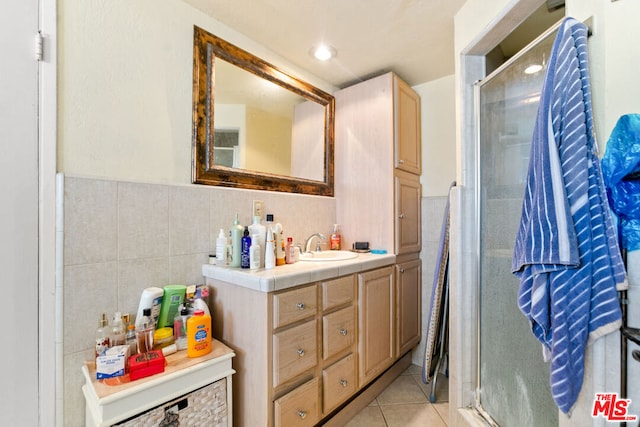 bathroom featuring tile walls, vanity, tile patterned flooring, and a shower with door