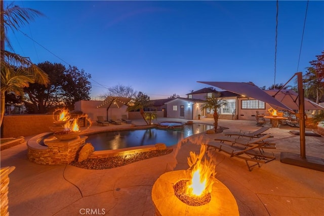 pool at dusk with a patio and an outdoor fire pit