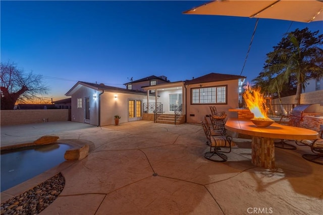 back house at dusk featuring an outdoor fire pit and a patio