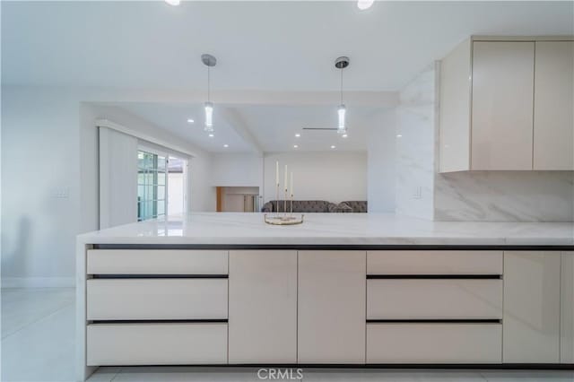 kitchen with white cabinetry, pendant lighting, light stone counters, and decorative backsplash