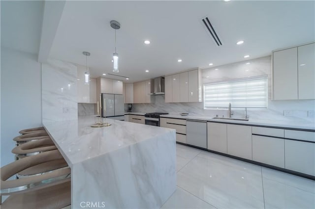 kitchen with sink, white appliances, white cabinetry, hanging light fixtures, and wall chimney exhaust hood