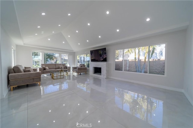 unfurnished living room featuring a wealth of natural light, high vaulted ceiling, and a premium fireplace