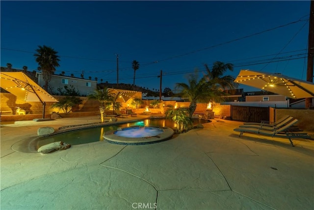 pool at night featuring a patio area