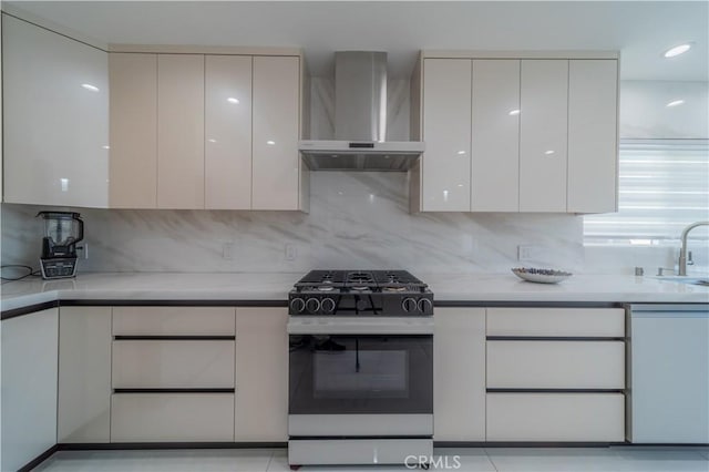 kitchen featuring white cabinetry, wall chimney range hood, tasteful backsplash, and gas range oven