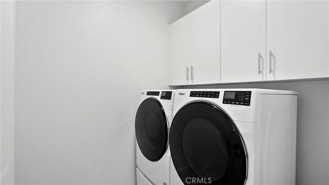 laundry room featuring washer and clothes dryer and cabinets