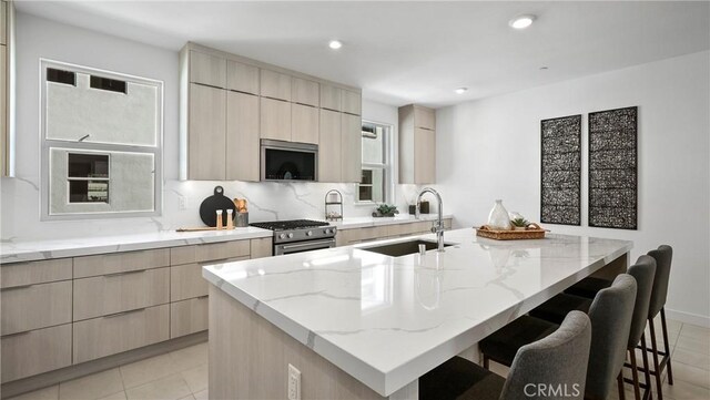 kitchen featuring a kitchen bar, appliances with stainless steel finishes, sink, and an island with sink