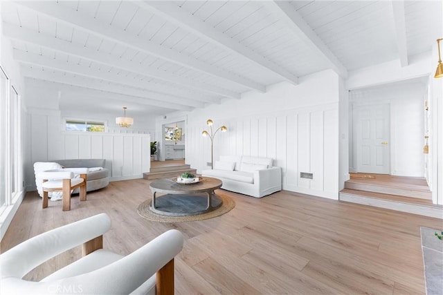 living room featuring a chandelier, beam ceiling, and light hardwood / wood-style flooring