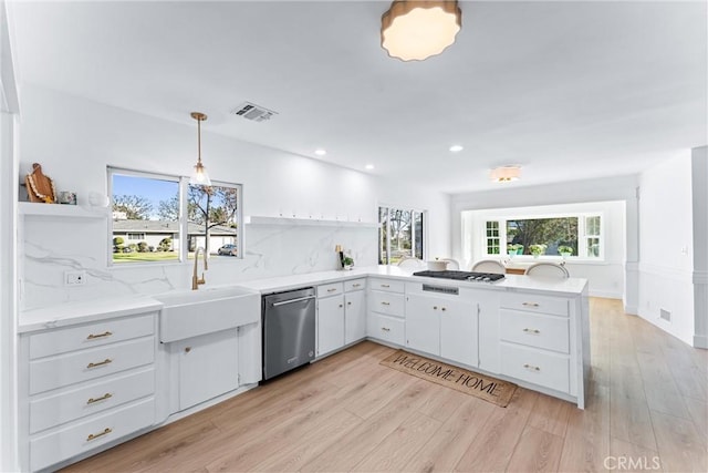 kitchen with sink, tasteful backsplash, hanging light fixtures, stainless steel dishwasher, and white cabinets